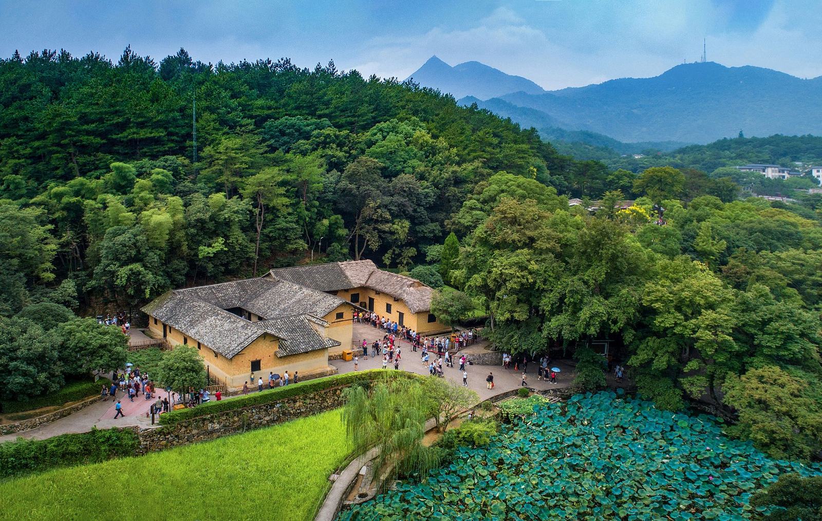 毛泽东故居实景：韶山冲上屋场的故居建筑群，青瓦土墙，前来参观的游客与周边青山荷塘