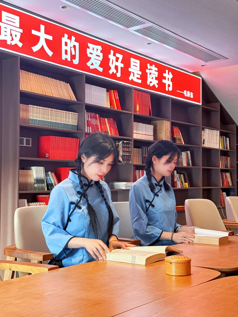 韶山会客厅会议图书室实景：整面藏书墙与长条会议桌，墙面标语“最大的爱好是读书”，可作小型会议与阅读空间